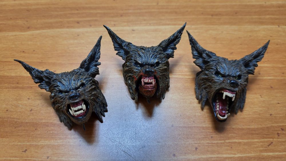 A view of the three heads, front side, with the clean closed mouth head on the left, the bloody mouth head in the middle (with jaw closed), and the open mouth head on the right